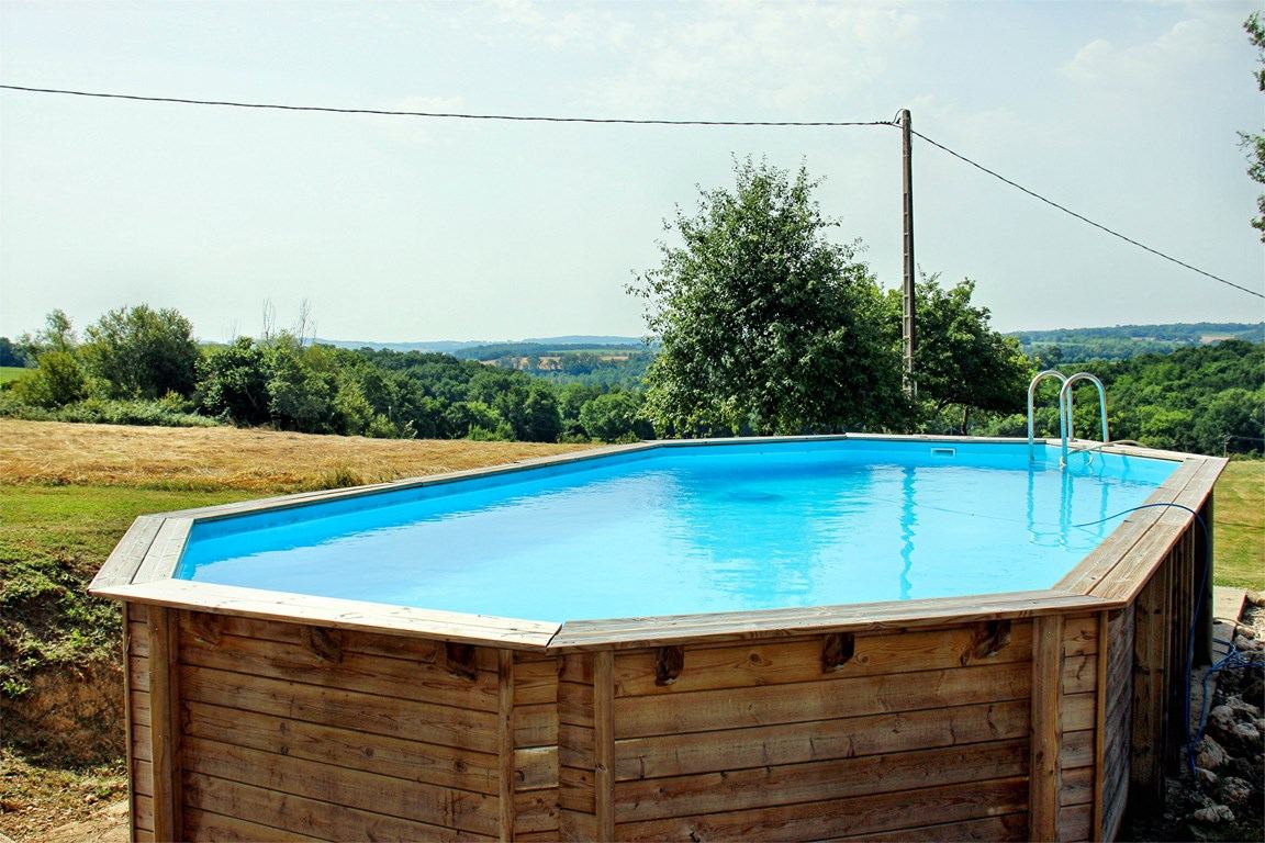 Grande piscine hors-sol du domaine de Hillon avec vue panoramique sur les collines