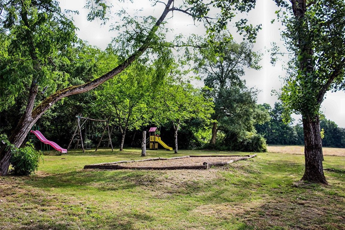 Aire de jeux pour enfants ombragée avec toboggan et balançoires